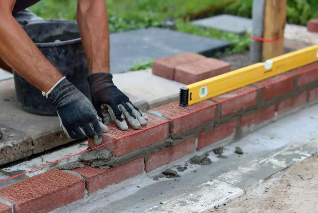 Bricklayer setting new brick with a level